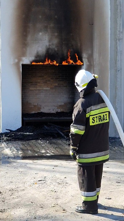 FOT. Ogień wydobywający się ze strefy pasa z wełny mineralnej po zakończeniu badania i ugaszeniu źródła ognia (Badania ICiMB); (źródło: PSPS)