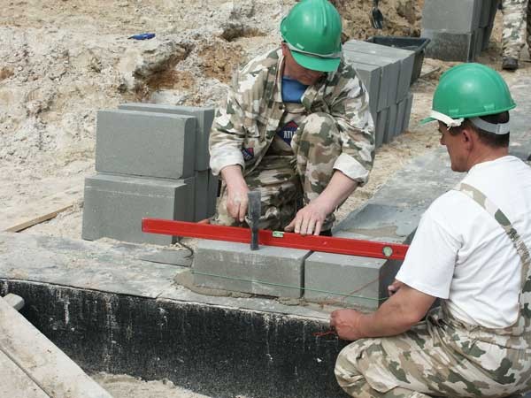 Murowanie ścian fundamentowych wymaga precyzji. Buduje się je najczęściej z bloczków betonowych. Obok dużej wytrzymałości na ściskanie, cechuje je też niewielka nasiąkliwość. Fot. ATLAS
