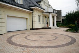 Dom stylizowany na dworek o zróżnicowanej bryle. Trapezowate kostki Piccola (pastello, kasztanowy) Libet Decco umożliwiają ułożenie nawierzchni o miękkich obłych wzorach